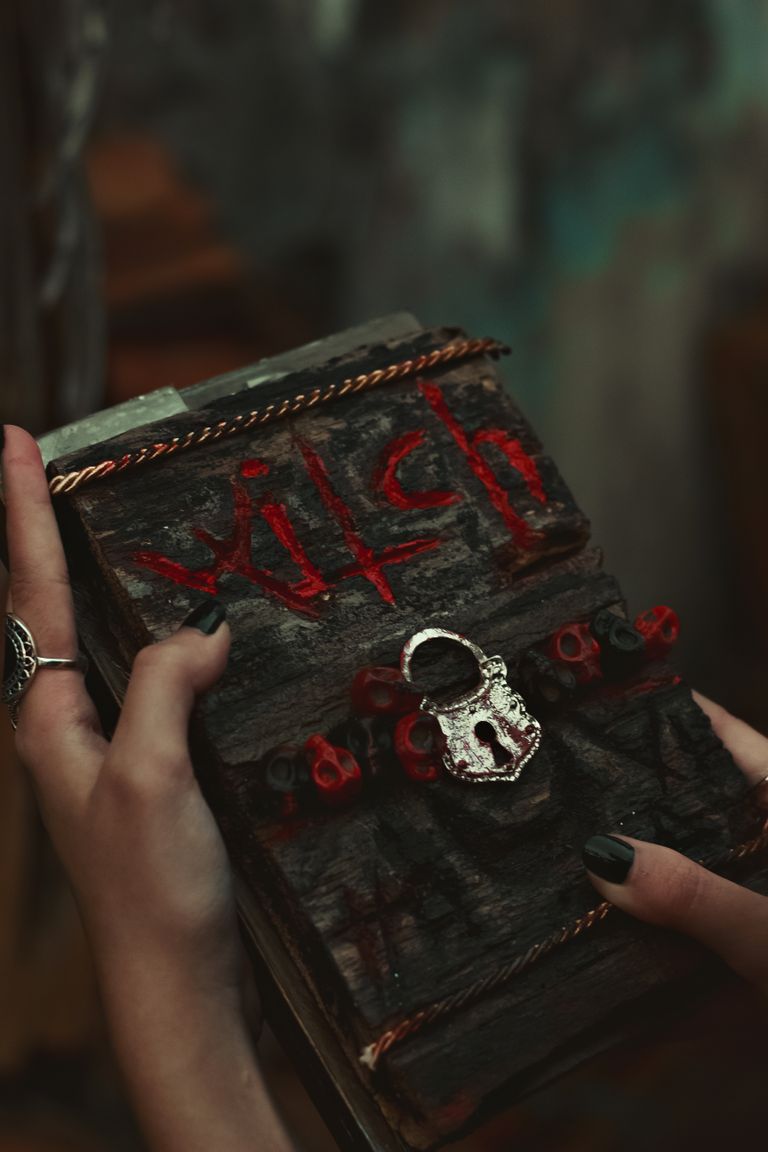 A mysterious locked spellbook being held by hands, evoking themes of magic and witchcraft.