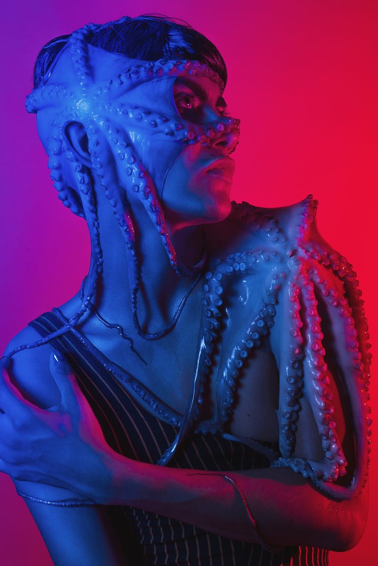 A mysterious portrait artfully blending human form with octopus tentacles under vivid lighting.